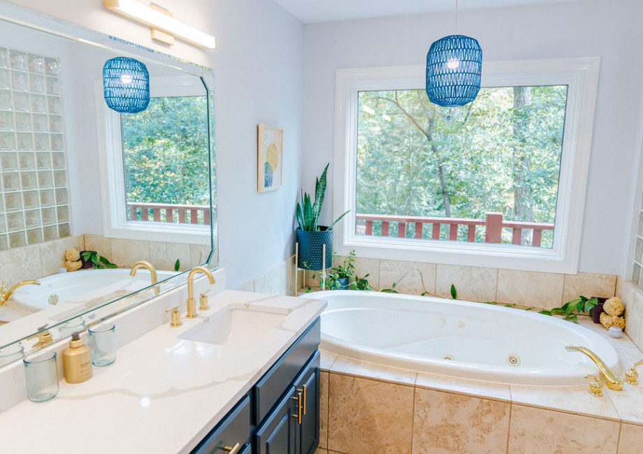 The master bath features a large, jetted soaking tub and walk-in shower, a picture window with views of the tree-covered hillside, and new quartz countertops and lighting.